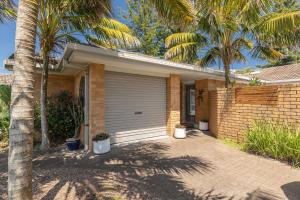 a brick house with a garage and palm trees at The Reef in Boomerang Beach