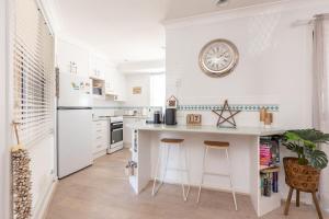 a kitchen with a counter and a clock on the wall at The Reef in Boomerang Beach +8 photos