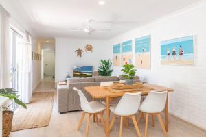 a living room with a wooden table and white chairs at The Reef in Boomerang Beach
