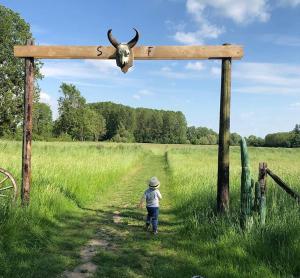 uma criança a atravessar uma cruz de madeira com uma vaca. em La Ferme des Isles em Authouillet