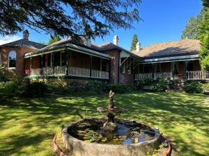 a house with a fountain in front of a yard at Rowan Brae Historic Guesthouse in Blackheath