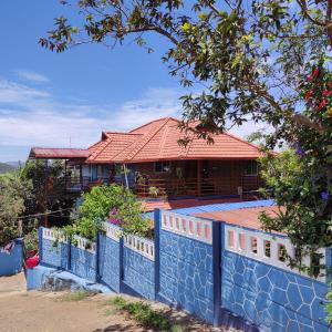 uma casa com uma cerca azul em frente em Hill View Homestay Madikeri Coorg em Madikeri