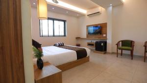 - une chambre avec un lit, une télévision et une chaise dans l'établissement Alleppey Haven Beach Villa, à Alappuzha