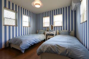 duas camas num quarto com paredes listradas azuis em Seaside House Enoshima 江ノ島, Free Parking 漫居湘南海岸, 尋訪灌籃高手 em Koshigoe