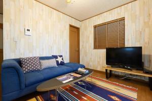 uma sala de estar com um sofá azul e uma TV em Seaside House Enoshima 江ノ島, Free Parking 漫居湘南海岸, 尋訪灌籃高手 em Koshigoe