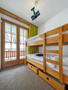 a bedroom with two bunk beds and a balcony at Les Mayens de l'Ours - At the foot of Piste de l'Ours' slope! in Agettes