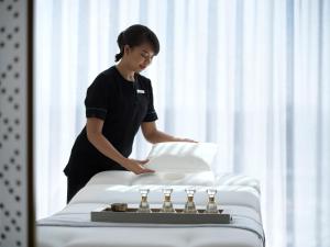 a woman standing next to a bed with pillows at Four Seasons Hotel Kuwait at Burj Alshaya in Kuwait