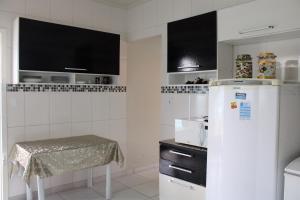 a kitchen with a refrigerator and a table in it at Casa com piscina à beira-mar in Itanhaém