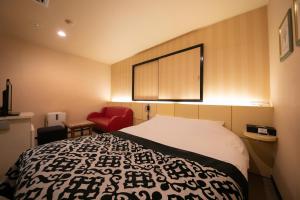 a hotel room with a bed and a red chair at Hotel Vanilla (Adult Only) in Ueda