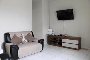 a living room with a chair and a flat screen tv at Casa com piscina à beira-mar in Itanhaém