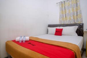 a bedroom with a bed with a red blanket on it at RedDoorz near Politeknik Manado in Paniki