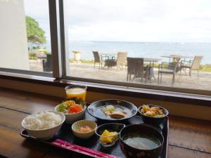 uma bandeja com tigelas de comida numa mesa em frente a uma janela em Hotel Oceans Nakijin em Nakijin