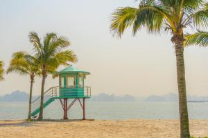 uma torre de salva-vidas numa praia com palmeiras em Haradise Suite Villa & Homestay Ha Long em Ha Long