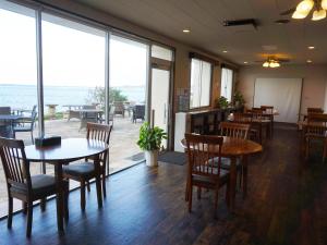 ein Restaurant mit Tischen und Stühlen und Meerblick in der Unterkunft Hotel Oceans Nakijin in Nakijin