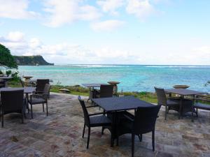 a patio with tables and chairs and the ocean at Hotel Oceans Nakijin in Nakijin
