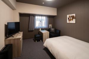 a hotel room with a bed and a television at Hotel Route Inn Matsuyama -Katsuyama Dori- in Matsuyama