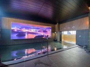 a large tv on a wall above a swimming pool at Hotel Route Inn Matsuyama -Katsuyama Dori- in Matsuyama