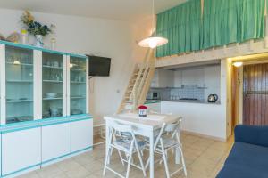 een keuken met blauwe kasten en een witte tafel en stoelen bij I Fari 48 600Mt From The Beach - Happy Rentals in Porto San Paolo