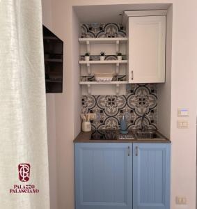 una cocina con armarios azules y platos en la pared en Palazzo Palasciano en Monopoli