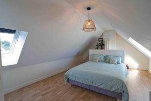 ein weißes Schlafzimmer mit einem Bett im Dachgeschoss in der Unterkunft Sea, Surf and Sun in Saint-Pierre-Quiberon