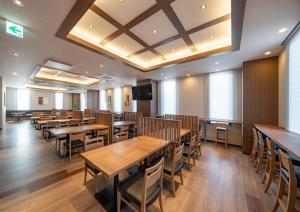 Hotel Route Inn Osaka Izumifuchu في Izumi: غرفة طعام مع طاولات وكراسي خشبية