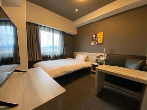 a hotel room with a bed and a flat screen tv at Hotel Route Inn Osaka Izumifuchu in Izumi