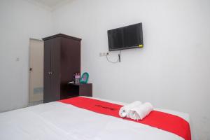 a bedroom with a bed and a flat screen tv at RedDoorz near De La Salle Manado in Manado
