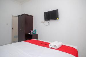 um quarto com uma cama e uma televisão de ecrã plano em RedDoorz near De La Salle Manado em Manado