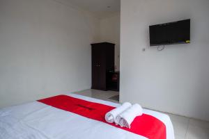 a bedroom with a bed with towels and a flat screen tv at RedDoorz near De La Salle Manado in Manado +25 photos