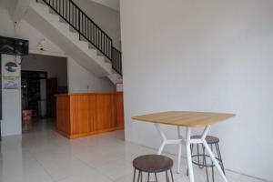 a table and two stools in a room with a staircase at RedDoorz near De La Salle Manado in Manado