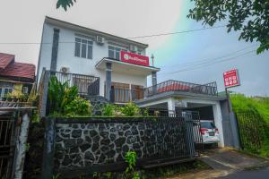 a white building with a fence in front of it at RedDoorz near De La Salle Manado in Manado