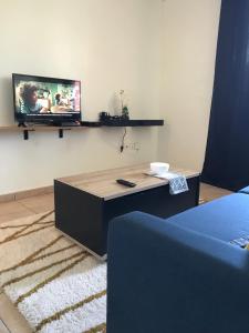 a living room with a table and a tv on the wall at Le Studio Cosy II - Sainte Clotilde in Saint-Denis