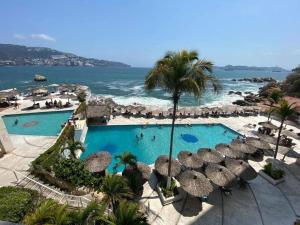 a view of a pool with umbrellas and the ocean at Hotel Torres Gemelas vista al mar a pie de playa in Acapulco