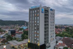 un edificio blanco alto con un cartel encima en BATIQA Hotel Lampung, en Bandar Lampung