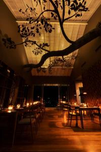 a room with tables and chairs and a tree hanging from the ceiling at Rivora Heights in Kandy