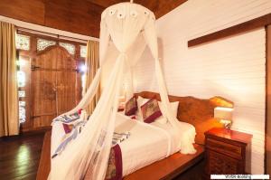 1 dormitorio con 1 cama con mosquitera en Warisan Villa By Reccoma, en Nusa Lembongan