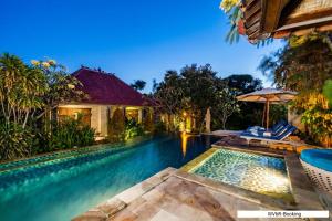 a swimming pool with chairs and an umbrella next to a house at Warisan Villa By Reccoma in Nusa Lembongan +49 photos