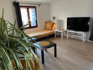 uma sala de estar com um sofá e uma televisão de ecrã plano em Chouett'Appart proche frontières em Village-Neuf