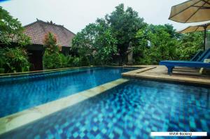 a swimming pool with a blue bench and an umbrella at Warisan Villa By Reccoma in Nusa Lembongan