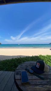a hat and a cell phone on a table next to the beach at Tiongman Scubadive & Lodge in Tioman Island