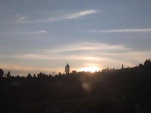 una puesta de sol en la cima de una colina con árboles en Refugio Flores de María, en Duitama