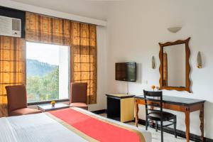 a hotel room with a bed and a desk and a window at Country Inn Nature Resort Bhimtal in Bhīm Tāl