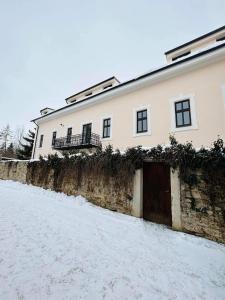 a white building with a gate in the snow at V ulicke in Kežmarok