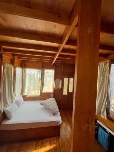 Cama en habitación con suelo y ventanas de madera en Mangrove Camp Fayoum, en ‘Ezbet Ilyâs