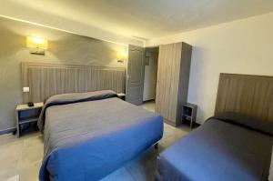 a hotel room with two beds in a room at Hotel Les Palmiers En Camargue in Saintes-Maries-de-la-Mer