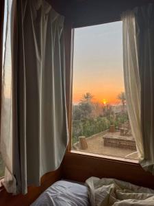 a bedroom with a window with a view of the sunset at Mangrove Camp Fayoum in ‘Ezbet Ilyâs