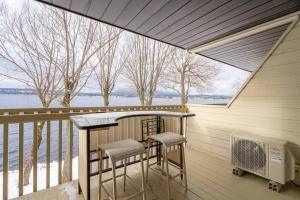 un porche con 2 taburetes y una mesa en el balcón en Au p'tit cocon sur le lac, en Magog-Orford