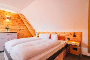 a bedroom with a white bed and a wooden wall at Hotel Andres in Bamberg