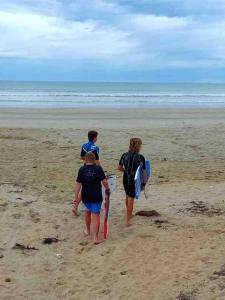 Tres personas caminando por la playa con sus tablas de surf en The Beach House, en Middleton