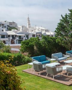 a group of blue chairs and tables on a lawn at Hotel Menorca Binibeca - Adults Recommended - by Pierre & Vacances Premium in Binibeca +99 photos